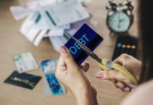 Woman hand cutting credit cards by scissors with calculator