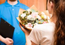 courier hands bouquet to young woman, flower delivery