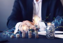 Businessman holding a bulb on top of coins stack for financial investment