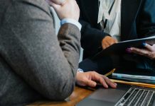 employee pointing at document while working in office with male colleague