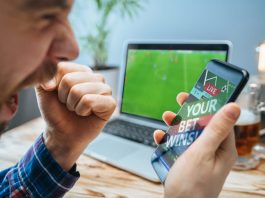 Lucky man celebrating victory after making bets using gambling mobile application on his phone.