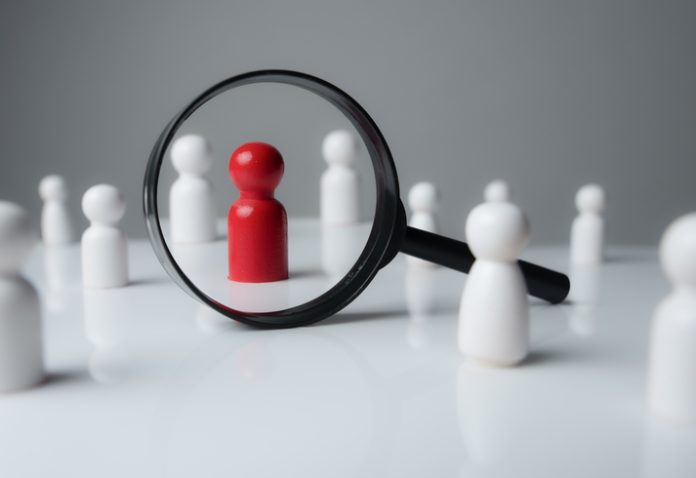 a magnifying glass looking to red wood people,Select a person in the team for a job