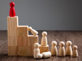 Wooden people figures on top of wooden block in the concept of leadership