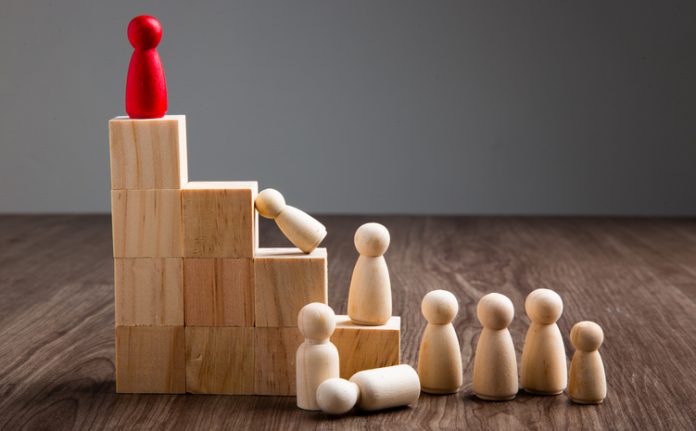 Wooden people figures on top of wooden block in the concept of leadership