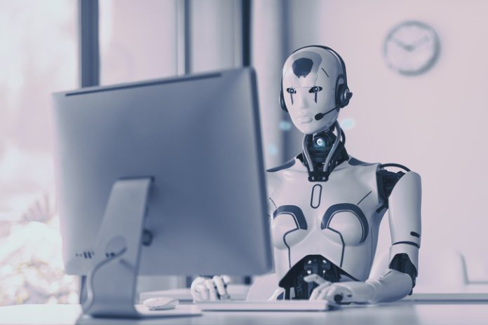 Android AI robot sitting at the desk and working in the office: artificial intelligence, business and automation concept