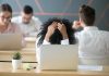 Frustrated african-american woman feeling burnout in shared office with laptop