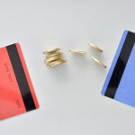 Bank cards are in the colors of living coral and blue with shiny yellow coins symbolizing the electronic exchange of money and balance.