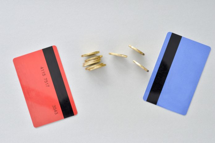 Bank cards are in the colors of living coral and blue with shiny yellow coins symbolizing the electronic exchange of money and balance.