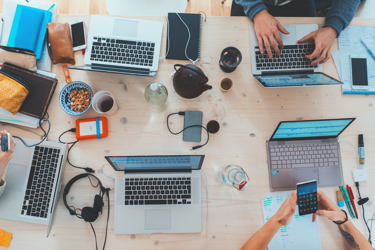 A group of professionals collaborating at a table, focused on laptops, enhancing knowledge management and information retrieval.