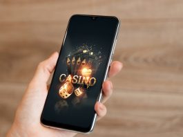 In the hands of a smartphone with playing cards the inscription casino, black-gold background.