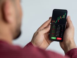 Middle-eastern businessman using trading application on smartphone for prop trading