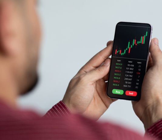 Middle-eastern businessman using trading application on smartphone for prop trading