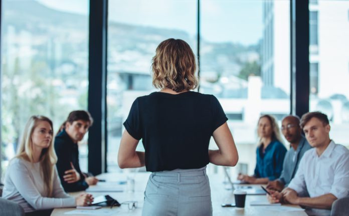 Woman addressing a meeting in office boardroom.