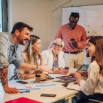 Diverse colleagues gathered in the office having a brainstorming while discussing new ideas for their new project. Multiracial coworkers gather in boardroom exchanging ideas at briefing.