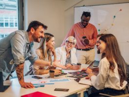 Diverse colleagues gathered in the office having a brainstorming while discussing new ideas for their new project. Multiracial coworkers gather in boardroom exchanging ideas at briefing.