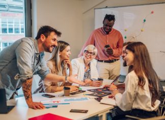 Diverse colleagues gathered in the office having a brainstorming while discussing new ideas for their new project. Multiracial coworkers gather in boardroom exchanging ideas at briefing.
