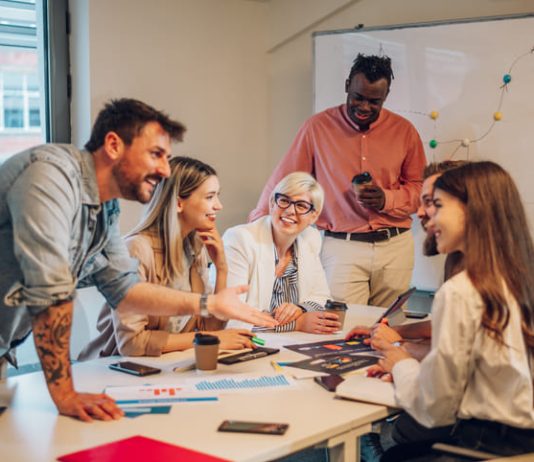 Diverse colleagues gathered in the office having a brainstorming while discussing new ideas for their new project. Multiracial coworkers gather in boardroom exchanging ideas at briefing.