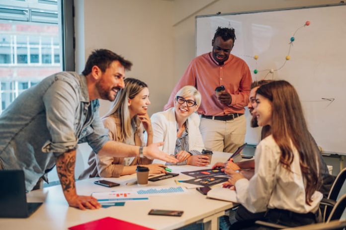 Diverse colleagues gathered in the office having a brainstorming while discussing new ideas for their new project. Multiracial coworkers gather in boardroom exchanging ideas at briefing.