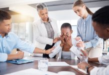 Emotional colleague being comforted by manager and co-workers