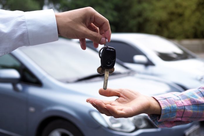 The car salesman and the key to the new owner.