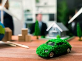EV car model on table with blurred business people planning business marketing for eco-friendly car in background. Greener future with alternative energy charge utilization in business