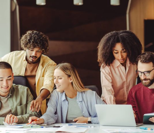 Diverse team of young Gen Z professionals collaborating on a project in a modern office