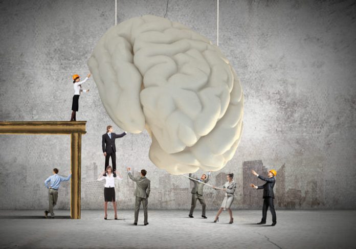 Huge human brain and many little businesspeople around. Concept of thinking new ideas