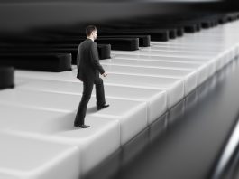 Side view of young businessman walking on abstract piano keys. Music, show business concept.
